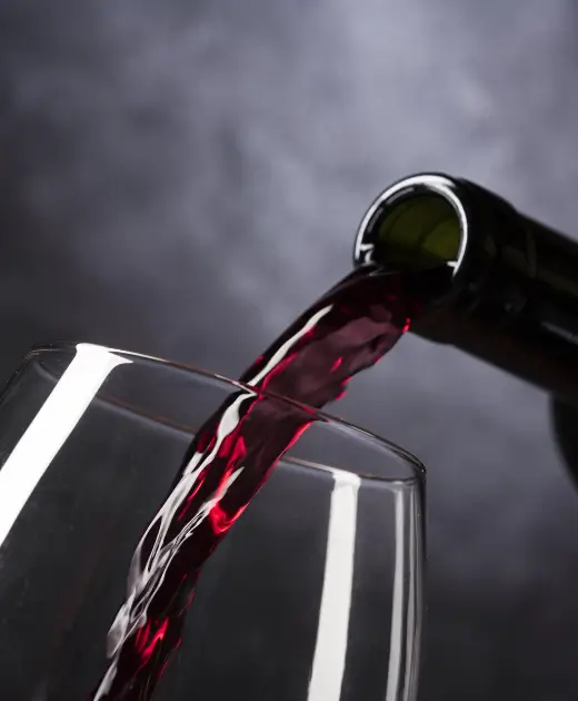 Red wine being poured from a bottle into a glass at Osiris Club Stanmore, symbolizing elegance and fine dining in a luxury bar setting.