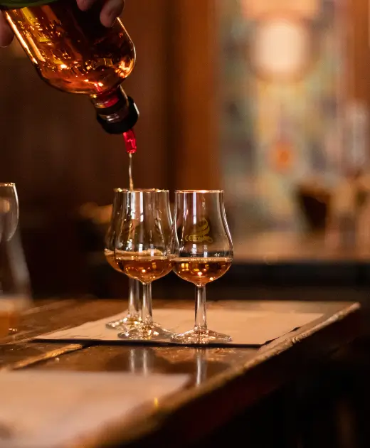 Premium whiskey being poured into elegant tasting glasses at Osiris Club Stanmore, showcasing luxury bar service and refined drink presentation.