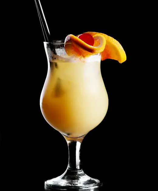 Chilled orange cocktail with ice, cherry garnish, and orange slice served in a hurricane glass on a black background.