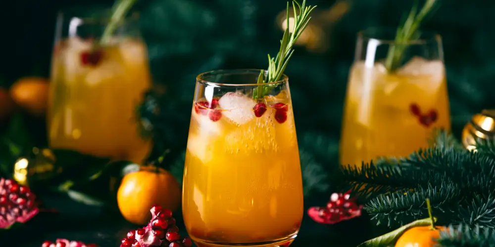 Festive orange cocktail with pomegranate seeds and rosemary garnish at Osiris Club Stanmore.